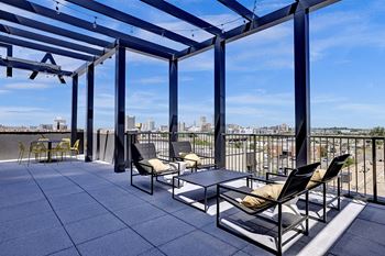 rooftop balcony with chairs and a table and a view of the city at Artisan Flats Apartments in Birmingham, AL